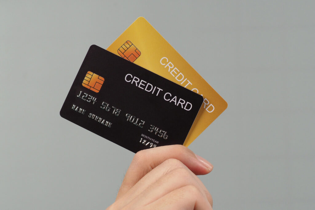 クレジットカードのイメージ。グレーの背景で手にクレジットカードを持っている様子