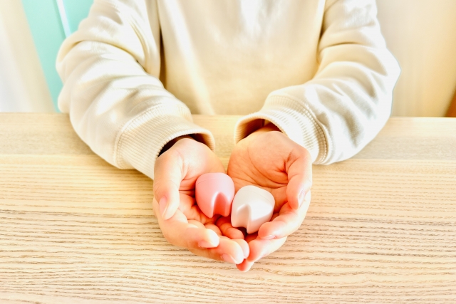 歯の模型を手のひらにのせている。抜歯を連想させる。