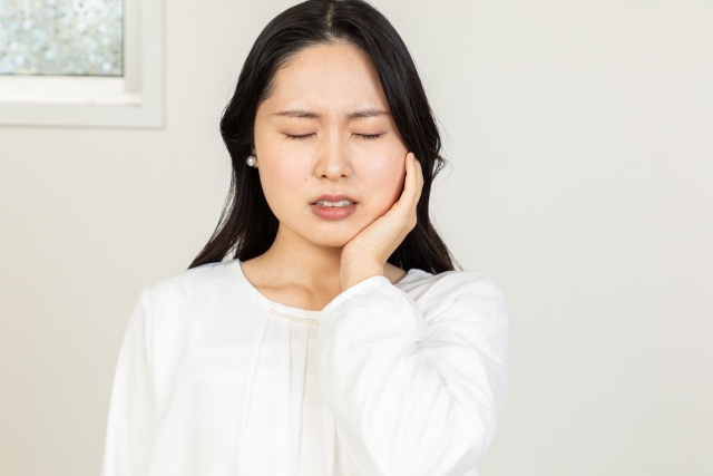 痛みがあり頬に手をあてる女性